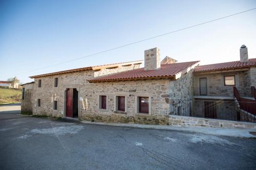 a stone building with a red door on a street at Casa Mirandês Rural in Miranda do Douro