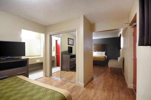 a hotel room with a bedroom with a bed and a mirror at Econo Lodge Inn & Suites I-35 at Shawnee Mission in Overland Park