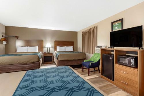 a hotel room with two beds and a flat screen tv at Econo Lodge Hays I-70 in Hays