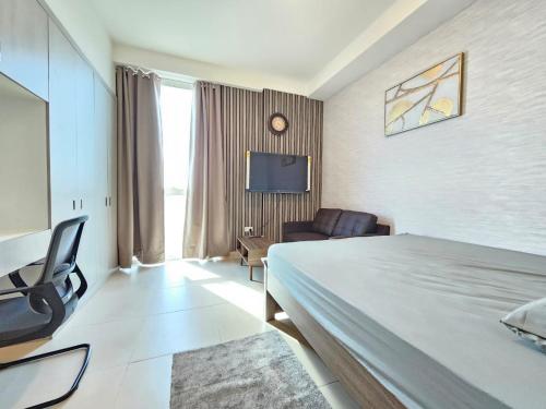 a hotel room with a bed and a chair and a tv at Studio KCA -601 in Abu Dhabi