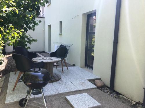a patio with a grill and chairs next to a building at Gite des 3 cigognes in Colmar