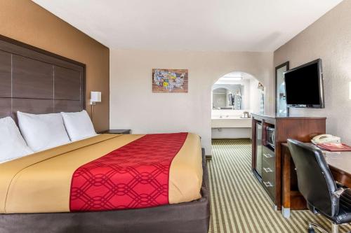 a hotel room with a bed and a desk and a television at Econo Lodge Winfield in Winfield