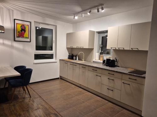 eine Küche mit weißen Schränken und einem Tisch darin in der Unterkunft Apartamenty Stynka Apartament Pod Gwiazdami in Misdroy