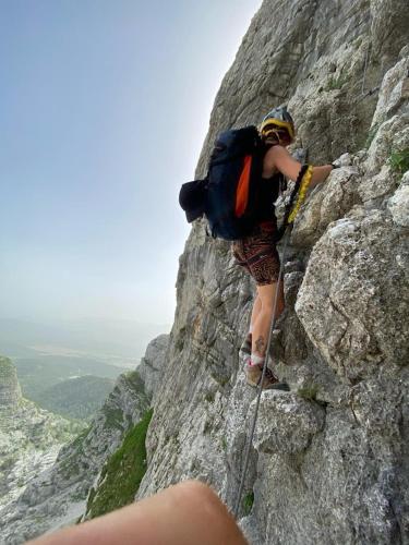 a person climbing up a rocky mountain with a backpack at Vila Agroturizam Kućica Mostar-Welcome bikers in Mostar