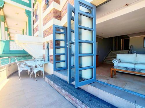 an open door to a patio with a table and a couch at Sunrise Deck Empire Apartment in Muizenberg