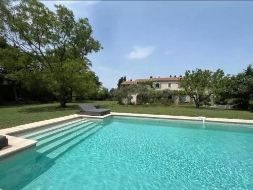une grande piscine avec une maison en arrière-plan dans l'établissement Charming house Saint Remy de Provence, à Saint-Rémy-de-Provence