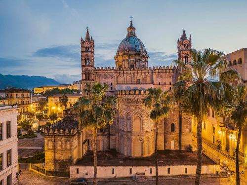 an old cathedral with palm trees in front of it at Grazioso appartamento non lontano dal mare in Trappeto