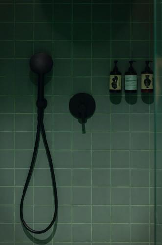 a green tiled wall with a shower in a bathroom at Heart Hotel in Limassol
