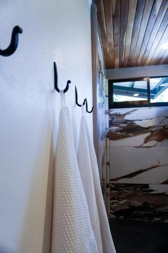 a bathroom with three white towels hanging on a wall at Sueño Río Celeste Boutique B&B in Bijagua