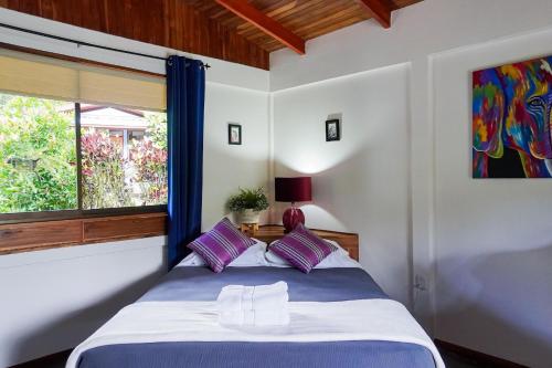 a bedroom with a bed with purple and white pillows at Sueño Río Celeste Boutique B&B in Bijagua