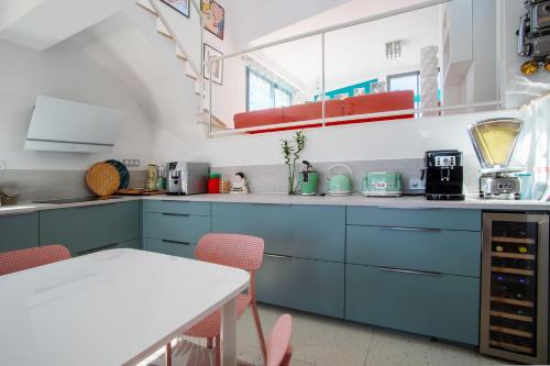 une cuisine avec des armoires bleues et une table blanche dans l'établissement Villa Seventy, à Frontignan