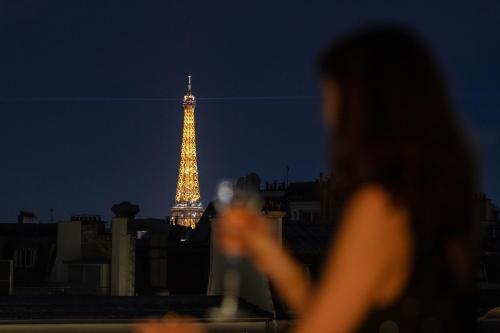 a woman looking at the eiffel tower at night at Hôtel Napoleon Paris in Paris