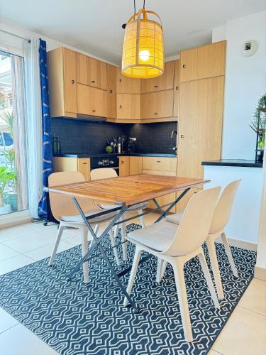 une cuisine avec une table et des chaises en bois sur un tapis dans l'établissement Gokotta, splendide T3 classé 3 étoiles, vue unique, piscine, garage, à Sète