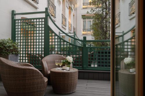 a patio with two chairs and a table with wine glasses at Hôtel Napoleon Paris in Paris