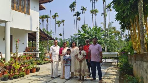 a family poses for a picture in front of a house at Ananda Holiday Home in Ambalavayal