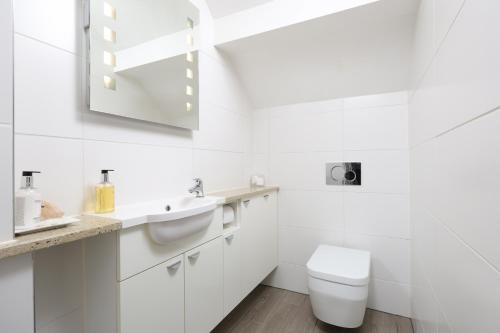 a white bathroom with a toilet and a sink at Berwick House in Sidmouth