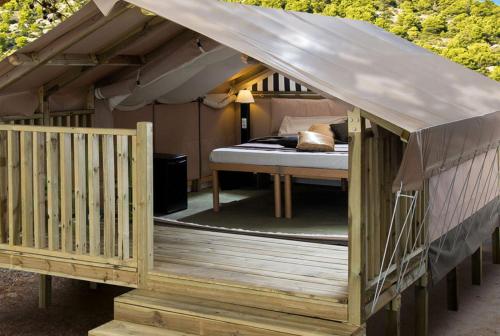a bed in a tent with a wooden deck at Camping Village Baia Azzurra in Castiglione della Pescaia