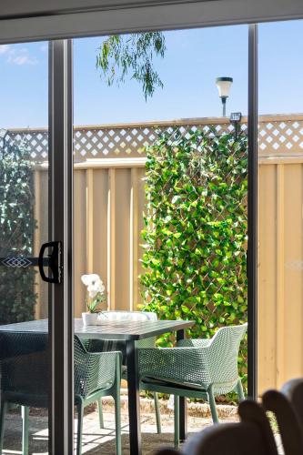 a patio with a table and chairs and a hedge at 62CapeView Geographe bay in Broadwater