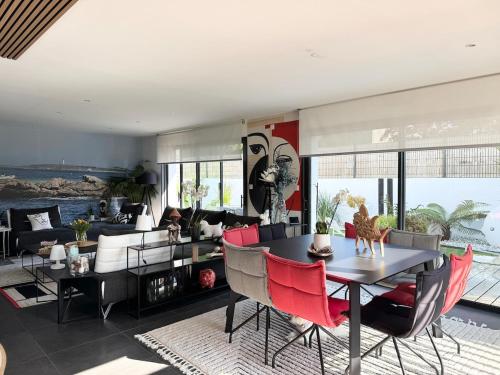 un salon avec une table et des chaises rouges dans l'établissement Belle maison spacieuse et jardin paysager, Gouesnac'h, à Gouesnach