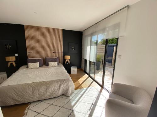 une chambre avec un lit et une chaise dans l'établissement Belle maison spacieuse et jardin paysager, Gouesnac'h, à Gouesnach