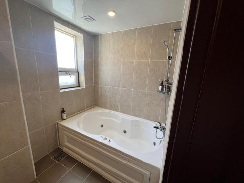 a bath tub in a bathroom with a window at Ramada Taebaek Hotel in Taebaek