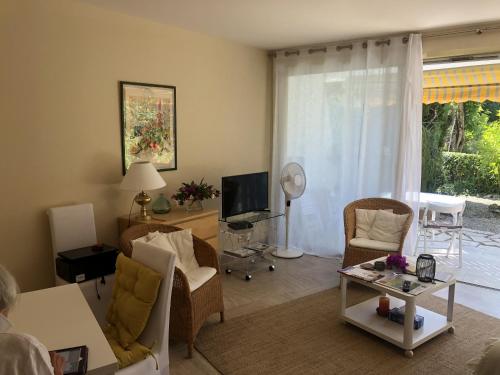 un salon avec un canapé, des chaises et une télévision dans l'établissement Les Oliviers 3, Domaine de Pierre Longue, à Cannes