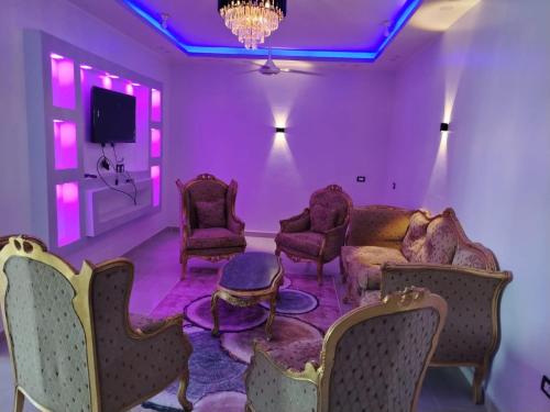 a room with chairs and a tv and purple lighting at Mena Palace Nile View in Luxor