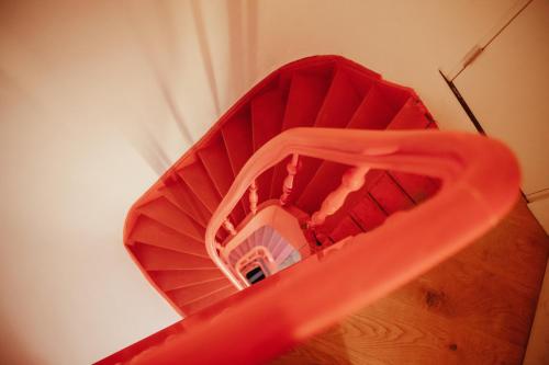 a spiral staircase with a red hand rail at A Place Antwerp - Boutique Suites & Flats - Oude Koornmarkt 1 in Antwerp