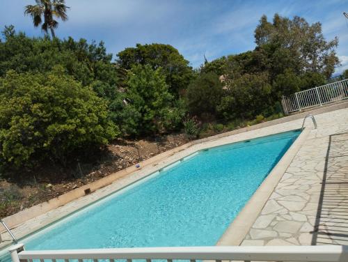 une piscine bleue avec des arbres en arrière-plan dans l'établissement Le Bleu Mer, aux Issambres