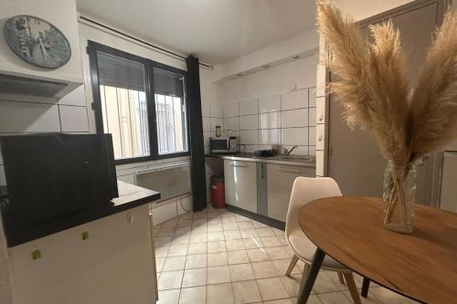 une cuisine avec une table et une horloge au mur dans l'établissement Le Moulin - Grand studio - Gare, à Narbonne
