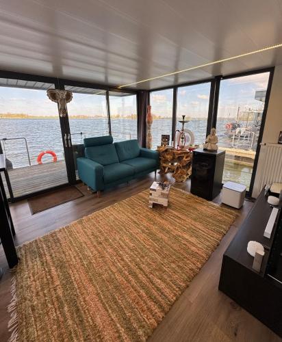 a living room with a blue couch on a boat at Exclusieve Houseboat La Mare 12 x 5 meter met sauna en hottup in Maasbommel