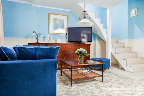 a living room with a blue couch and a tv at Hotel Seehof Leipzig in Zwenkau