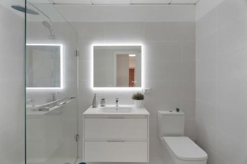 a white bathroom with a toilet and a sink at Apartamento Bonjour in Candelaria