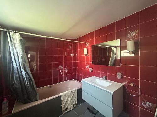 La salle de bains rouge est pourvue d'un lavabo et d'une baignoire. dans l'établissement Maison 3 chambres hyper centre, à Cabourg