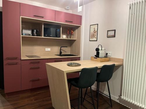 a kitchen with purple cabinets and a wooden table with two chairs at La Promenade in Beaupréau