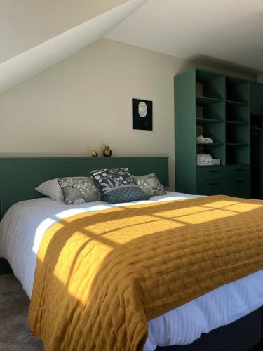 a bedroom with a large bed with a yellow blanket at La Promenade in Beaupréau