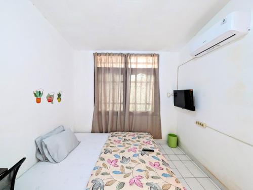 a small bedroom with a bed and a television at Homey Guesthouse Sukomanunggal Syariah in Surabaya