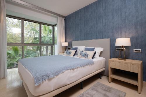 a bedroom with a bed with blue walls and a window at Luxury apartment in Jardines del Principe in Marbella