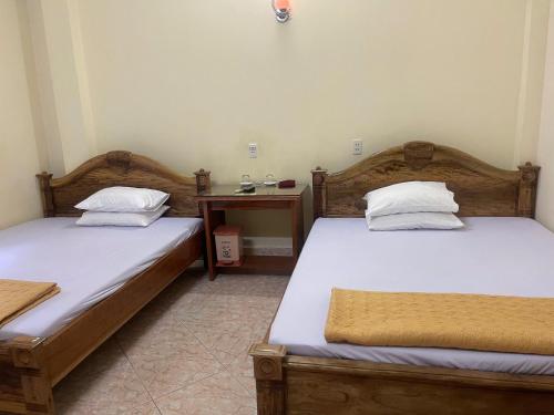 two twin beds in a room with a table at Nhà Nghỉ Thanh Mai in Bản Có