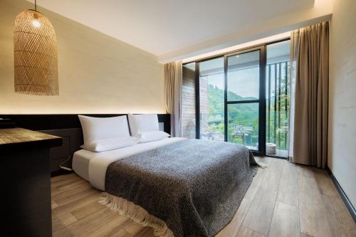 a bedroom with a bed and a large window at 青城山坐忘森林疗愈酒店 in Dujiangyan