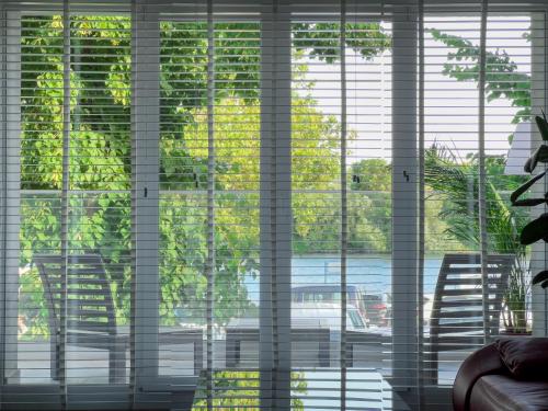 a window with blinds on it looking out at a street at Modernes Wasserfront Wohnung, Terrasse, Parkplatz in Flörsheim