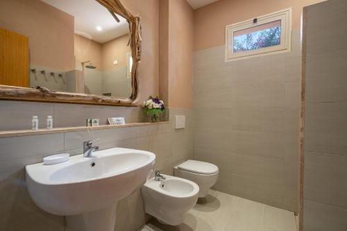a bathroom with a sink and a toilet and a mirror at Hotel Villaggio Cala Di Volpe in Capo Vaticano