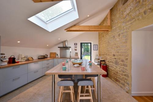 - une cuisine avec une table et des tabourets en bois dans l'établissement Longère Kerinis - Maison avec grand jardin, à Locmariaquer