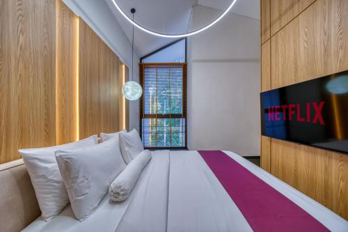 a bedroom with a large white bed with a television at Loyo Villas in Tegalalang
