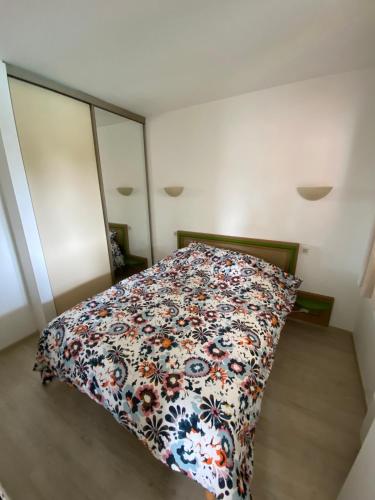 une chambre avec un lit avec un couvre-lit fleuri dans l'établissement Appartement Vue piscine climatisé wifi, à Saint-Raphaël
