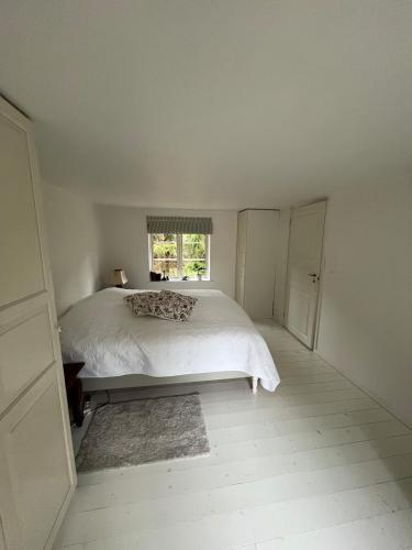 a white bedroom with a bed and a window at Hyggeligt hus in Lilla Stockhult