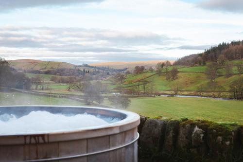 a hot tub with a view of a field at Wesleyan Bolton Abbey Estate in Appletreewick