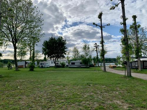 a park with two rvs and trees and a road at Camping Point Vert in Serrières-de-Briord