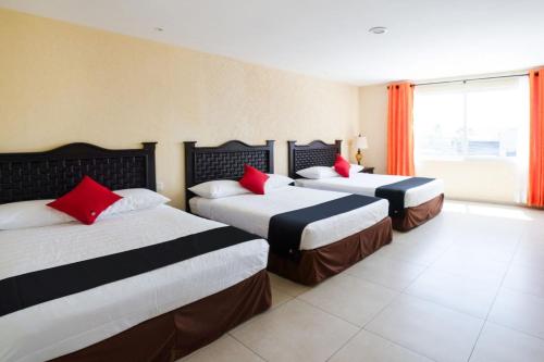 a hotel room with two beds with red pillows at Capital O Hotel Los Caracoles, Acapulco in Acapulco