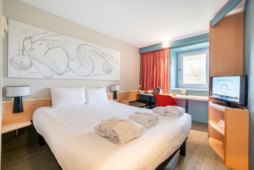 une chambre d'hôtel avec un lit et une télévision dans l'établissement ibis Antibes Sophia-Antipolis, à Valbonne